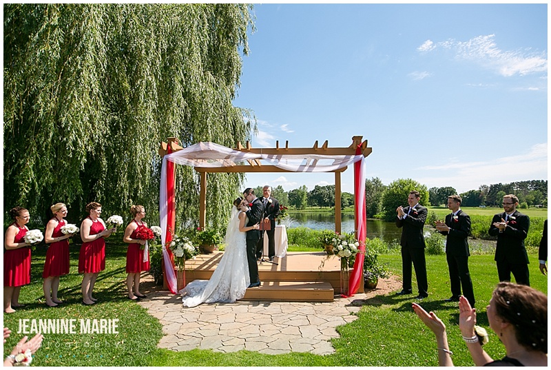 pergola site, Majestic Oaks Golf Club, summer wedding, red wedding, red bridesmaids, outdoor wedding, bride, groom, kiss