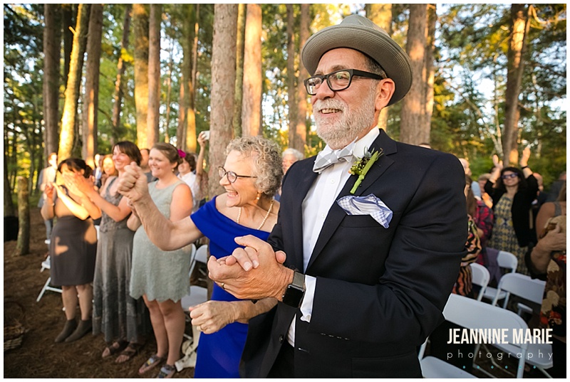 wedding guests, clapping, smiling, wedding ceremony, Camp Thunderbird, Lumberjack wedding, camping wedding, woodsy wedding, wedding in the woods, Bemidji wedding, Bemidji wedding photographer, Minnesota wedding photographer, Jeannine Marie Photography, summer wedding, plaid wedding, outdoor wedding, Up North wedding, Northern Minnesota wedding, Jewish Wedding, KD Floral, Fozzies BBQ, The Lost Walleye Orchestra, The Party Store, Crystal Greene, Anthropologie, Minnesota wedding