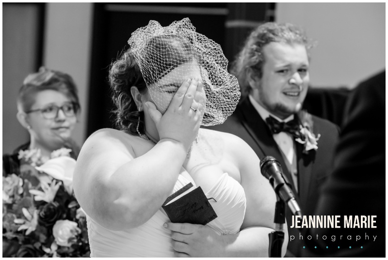 bride, hand over face, birdcage veil, laughing, crying, black and white photo, Woodbury Central Park, indoor wedding venue, indoor amphitheater, winter wedding, evening wedding, jewel-toned floral, Dorothy Ann Bakery, Green Mill Catering, Wedding Connection, Black Suit, Steve Madden, intimate wedding, Jeannine Marie Photography, Saint Paul wedding photographer, Minnesota wedding photographer