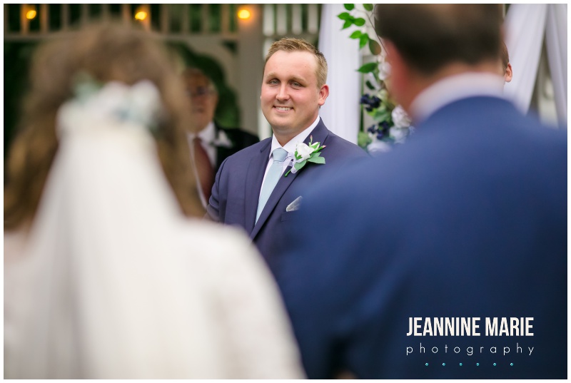 groom, boutonniere, smiling, bride walking down aisle, Mystical Rose gardens, fairytale wedding, outdoor wedding, outdoor Wisconsin wedding venue, Cinderella wedding, blue wedding, greenery, Cinderella carriage, lace ballgown, Jeannine Marie Photography, Wisconsin wedding photographer, covid wedding, pandemic wedding, romantic wedding, Dorothy Ann Bakery, Men's Wearhouse, Bella Bridal boutique, Creative Catering by Molly, Anna May Flowers, Men's Wearhouse, JJ's House, Zazzle, James Allen, Wisconsin Bride, wedding inspiration, wedding planning