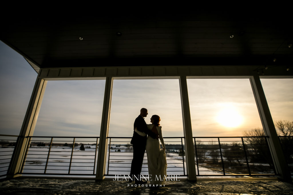 Couple posing in front of sunset at wedding for photographer Jeannine Marie Photography in Saint Paul